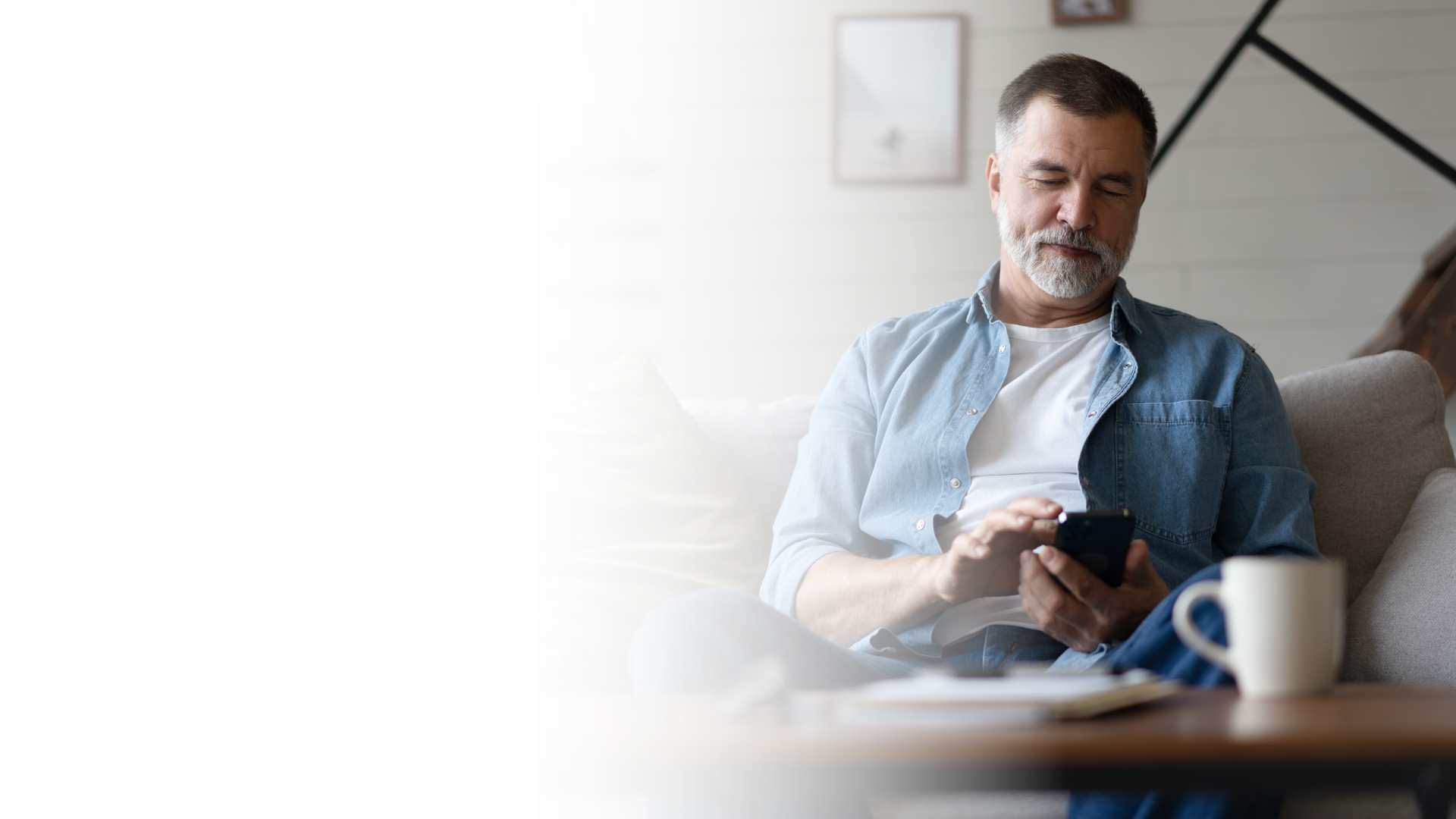 En mann leser på mobiltelefonen sin